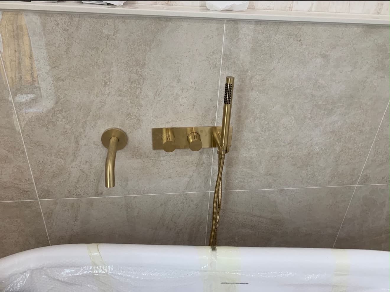 Wall-mounted brushed brass tub spout, controls and hand shower