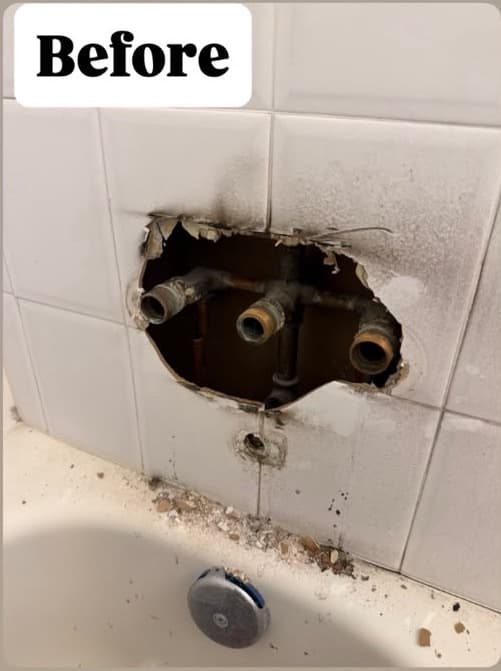 Tub and shower valve exposed through an opening in the tile wall before the repair